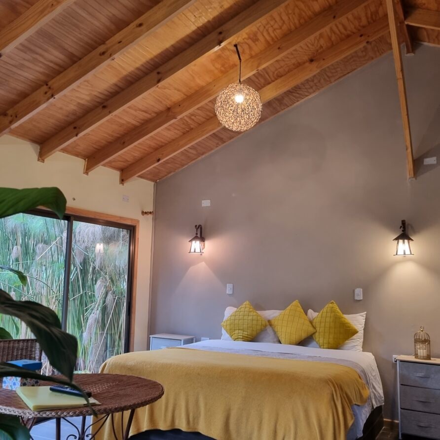 Dormitorio de la Cabaña Premium en Olmué — cama matrimonial y ventanal al jardín