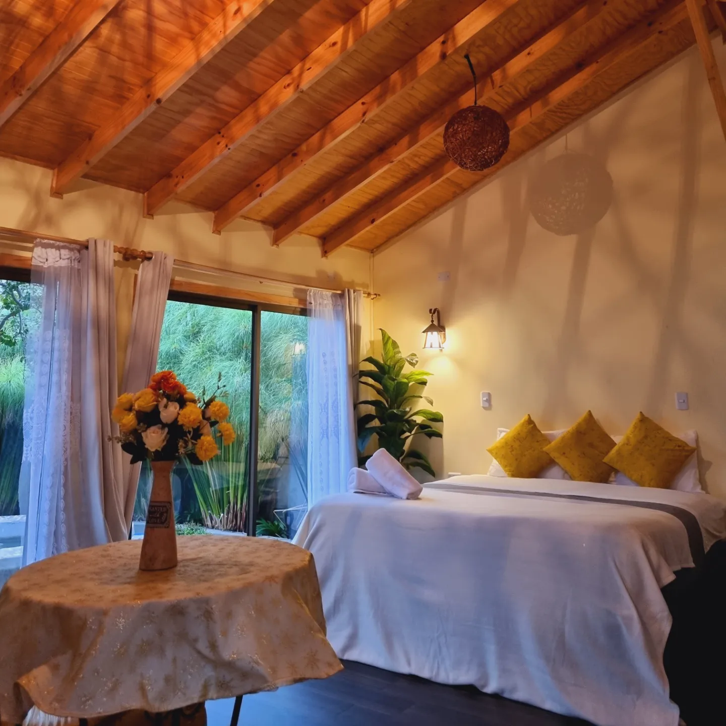 Dormitorio de la Cabaña Premium — vigas de madera a la vista y mesa junto al ventanal