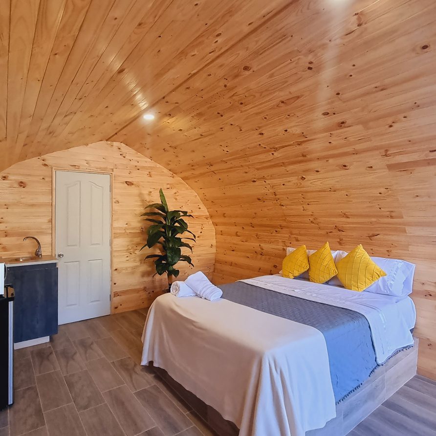 Dormitorio de la Tiny House en Olmué — cama matrimonial bajo el techo en arco de madera
